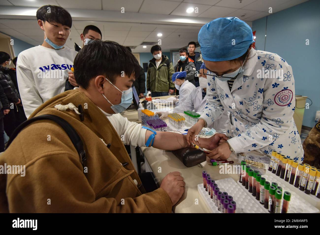 Fuyang, China. 12. Januar 2023. Eine Krankenschwester entnimmt einem jungen Mann Blut für ein paar Gesundheitschecks, bevor er ins Militär eingeliefert wird. Diese jungen Menschen wollen Soldaten werden, aber sie müssen sich strengen physischen und anderen Kontrollen unterziehen, bevor sie Soldaten werden können. Kredit: SOPA Images Limited/Alamy Live News Stockfoto