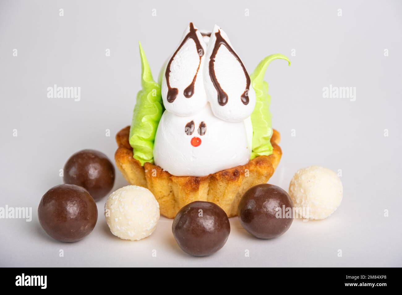 Hausgemachter Proteinkuchen in Form eines Osterhasen, der auf einem Keks liegt, wie in einem Nest inmitten von runden Schokoladen. Süße Ostertradition. Frühling Stockfoto