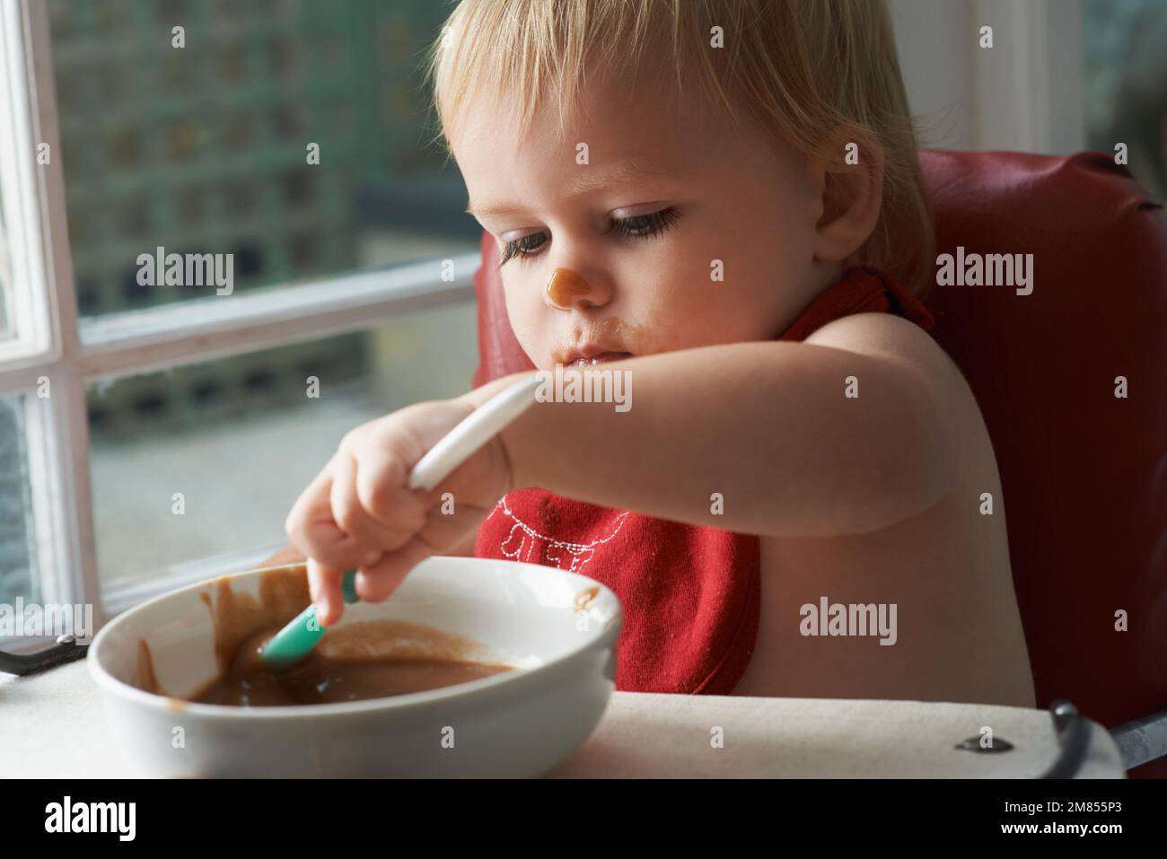 Wachsender Junge braucht sein Essen. Ein kleiner Junge, der in seinem Hochstuhl nach Herzenslust isst. Stockfoto