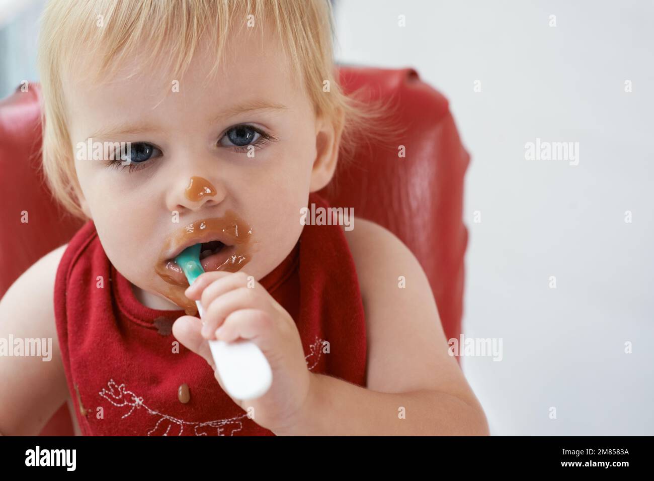 Wachsender Junge braucht sein Essen. Ein kleiner Junge, der in seinem Hochstuhl nach Herzenslust isst. Stockfoto