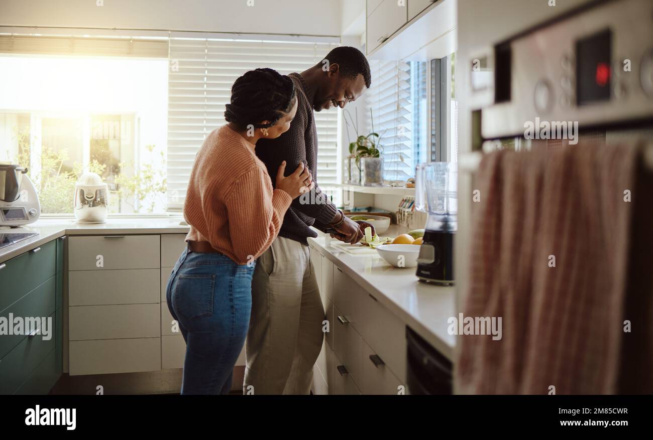 Schwarzes Paar, Kochen und mit Essen in der Küche zu Hause helfen, während zusammen, um gesundes Essen zu kochen. Glücklicher junger Mann und Frau in ihrem Haus oder Stockfoto