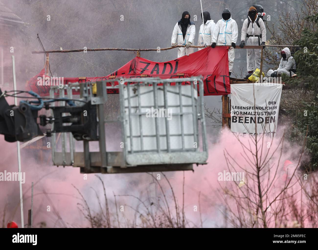 Erkelenz, Deutschland. 12. Januar 2023. Aktivisten entzünden am zweiten Tag der Räumung in dem Braunkohlendorf Lützerath, das von Klimaktivisten besetzt ist, die Pyrotechnik. Das Energieunternehmen RWE will die unter Lützerath liegende Kohle ausheben - zu diesem Zweck soll das Weiler auf dem Gebiet der Stadt Erkelenz am Braunkohlebergwerk Garzweiler II abgerissen werden. Kredit: Rolf Vennenbernd/dpa/Alamy Live News Stockfoto