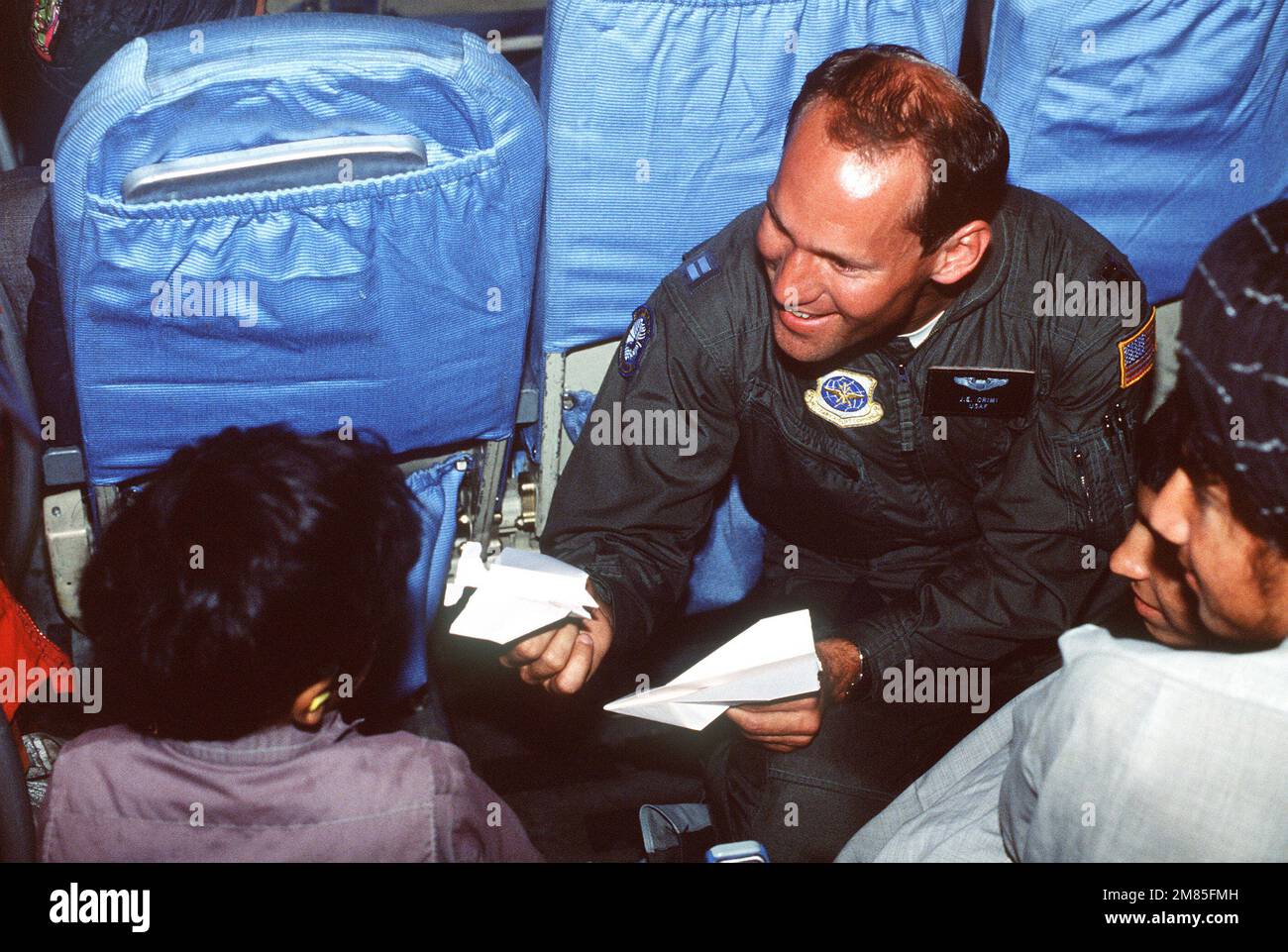 Hauptmann J.E. Crimi, Militärflugkommando, unterhält ein afghanisches Kind während eines Fluges an Bord eines C-141B-Starlifter-Flugzeugs. Das Kind ist eines von 25 afghanischen Zivilisten, die in das US Air Force Regional Medical Center in Weisbaden, Westdeutschland, zur spezialisierten medizinischen Behandlung nach Verletzungen, die infolge des afghanischen Bürgerkriegs entstanden sind, transportiert werden. Die Patienten werden später in Krankenhäuser in Europa und den Vereinigten Staaten evakuiert, um medizinische Hilfe zu spenden. Land: Unbekannt Stockfoto