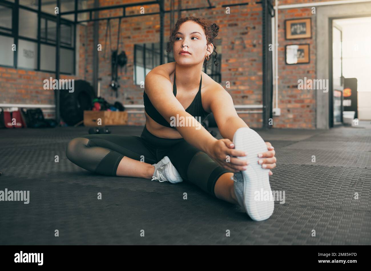 Fitness-Frau, Training und Stretching im Fitnessstudio für Warm-Up-Training und Training für Gesundheit, Balance und Wellness. Sportlerin oder Sportlerin auf dem Boden Stockfoto