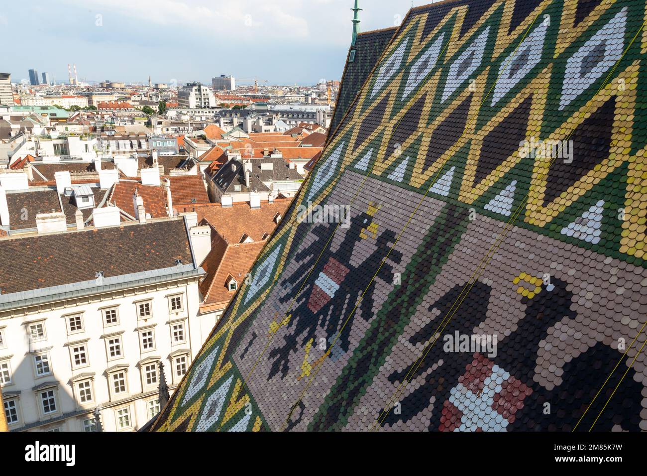 Von der Spitze des Stephansdoms in Wien, ein wunderschönes Fliesendach, Blick auf die Stadt und einige Arbeiter, die Wartungsarbeiten hoch über der Stadt durchführen Stockfoto