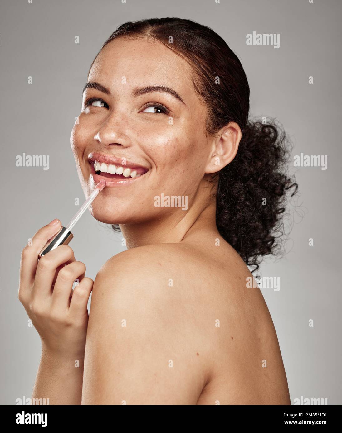 Frauen-, Lippenstift- und Kosmetikartikel für die Hautpflege oder Leuchten vor grauem Studiohintergrund. Glückliche Frau, die mit Zähnen lächelt, in Befriedigung für Stockfoto