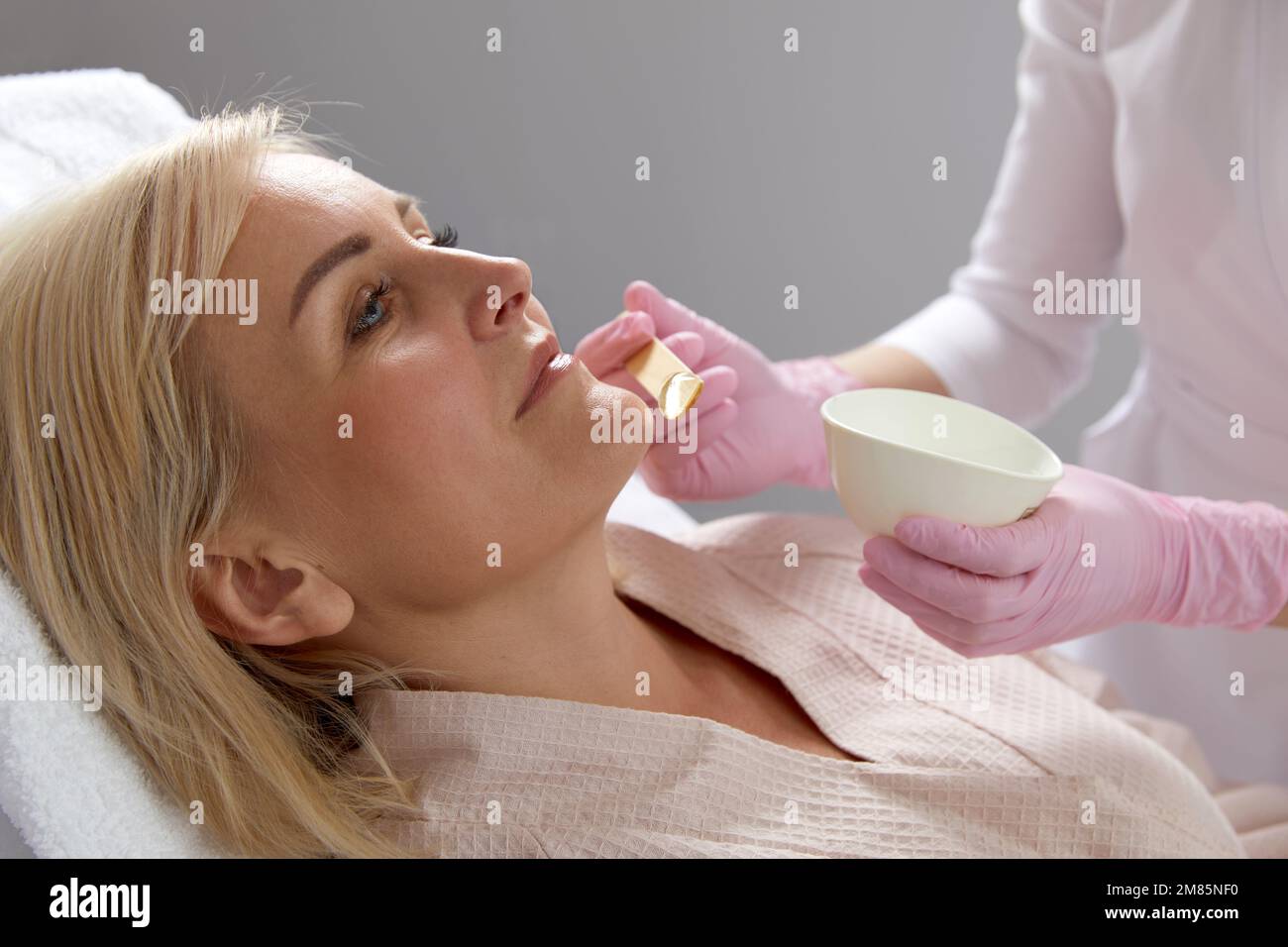Kosmetologe, die Gel o weibliches Gesicht vor der Laserbehandlung in der modernen Kosmetologischen Klinik auftragen Stockfoto