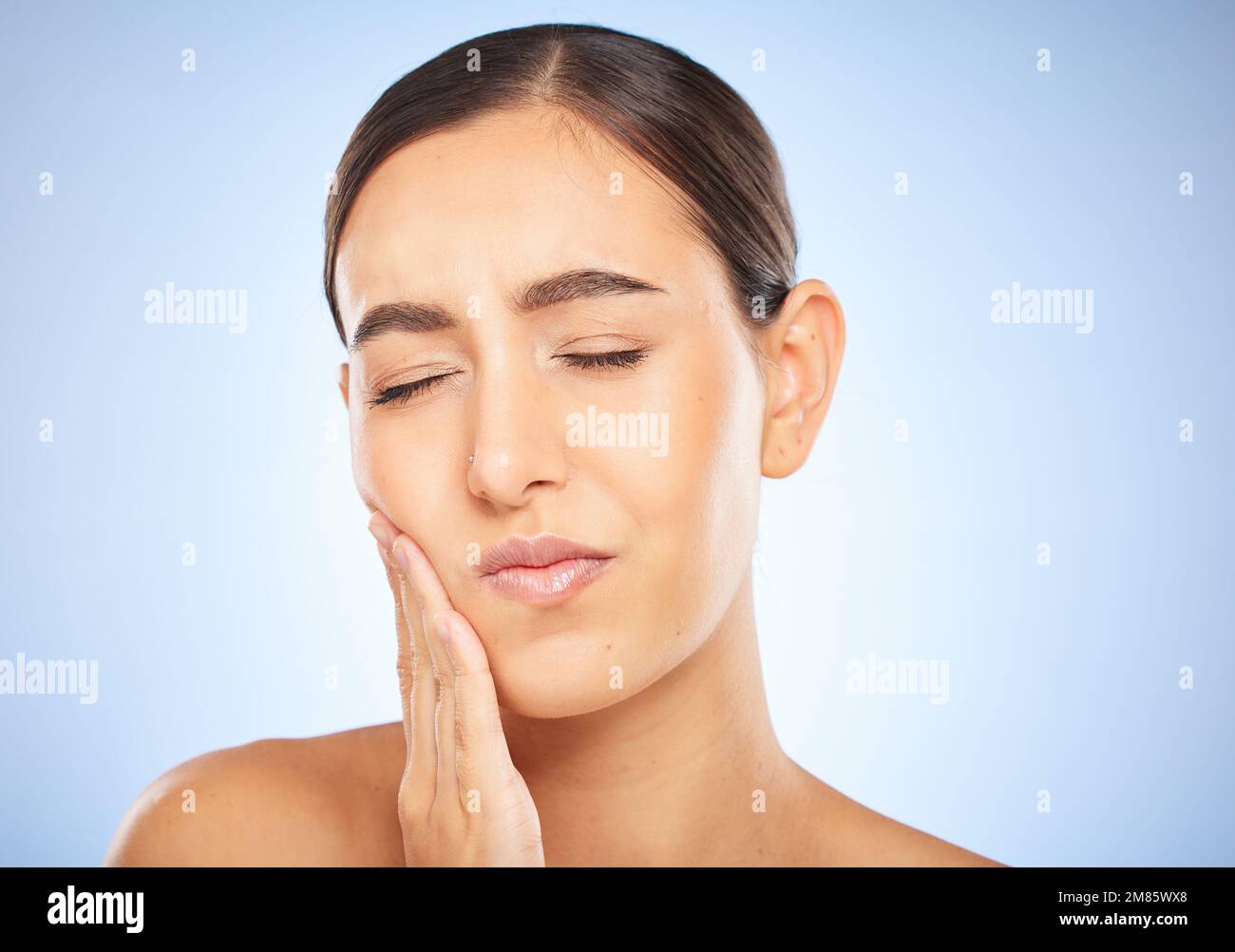 Zahnschmerzen, Schmerzen und Hohlraum mit einer Modellfrau, die ihren Mund im Studio auf blauem Hintergrund für die Mundpflege hält. Zahnhygiene, Plaque und Gesicht mit einem Stockfoto