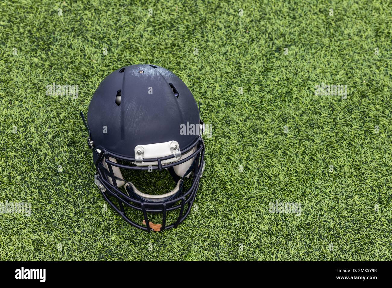 Ein einzelner American Football-Helm, der auf dem Gras liegt Stockfoto