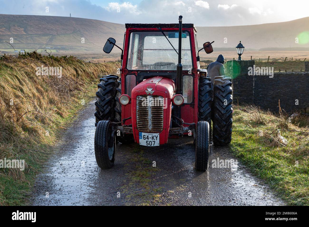 County Kerry, Irland, 12/01/2023, kleiner roter Traktor auf einer Landstraße im County Kerry, Irland nach einem Sturm Stockfoto
