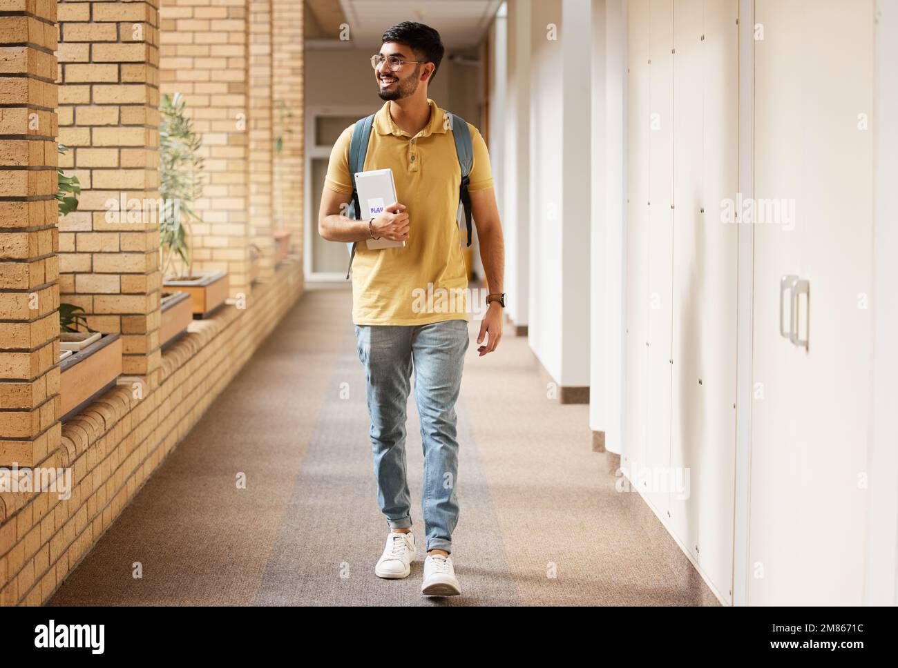 Universitätsstudent, College und indischer Mann, der mit einem Lächeln und Rucksack den Campus-Korridor hinunter läuft. Gen z männlich glücklich über Bildung, Lernen und Stockfoto