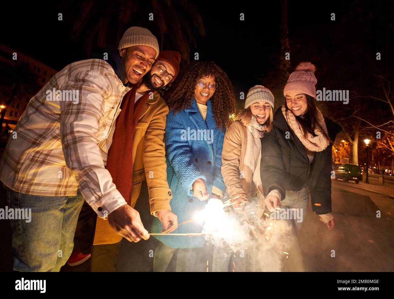 Eine Gruppe von Freunden feiert mit einem Feuerwerk bei der Abendparty. Menschen unterschiedlicher ethnischer Herkunft Stockfoto