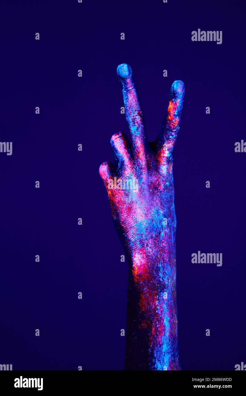 Hand mit zwei Fingern hoch in Frieden oder Sieg Symbol das Zeichen für V-Buchstaben in Gebärdensprache. Scheren-Geste. Nahaufnahme weiblicher Hände mit fluoreszierendem b Stockfoto