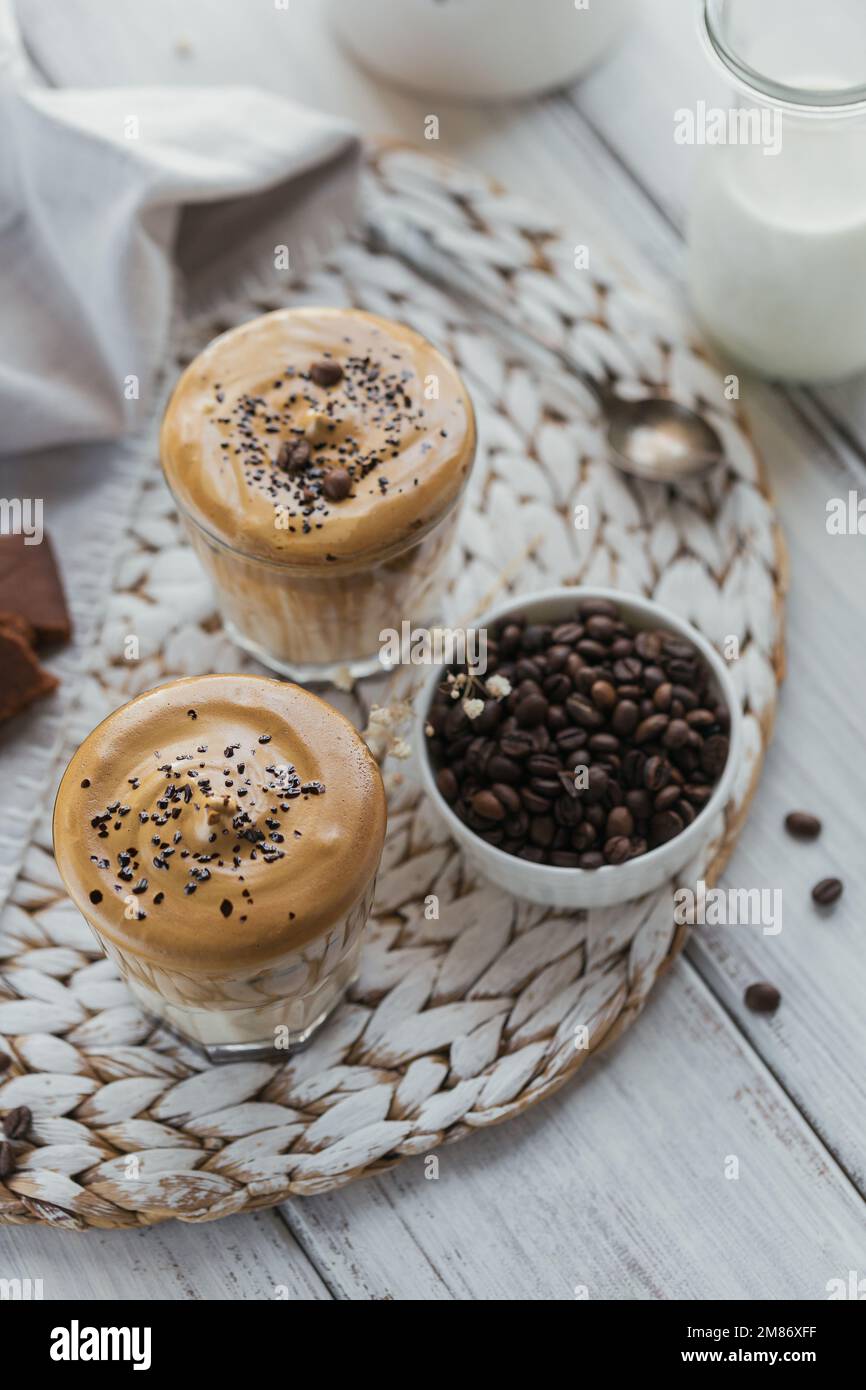 Dalgona schlug Kaffee, Instant, Sahne, Eiskaffee. Cocktail mit Kaffee, Milch und Eiswürfeln auf einem Modell mit hellem Hintergrund. Trendiger Hintergrund für Drinks Stockfoto