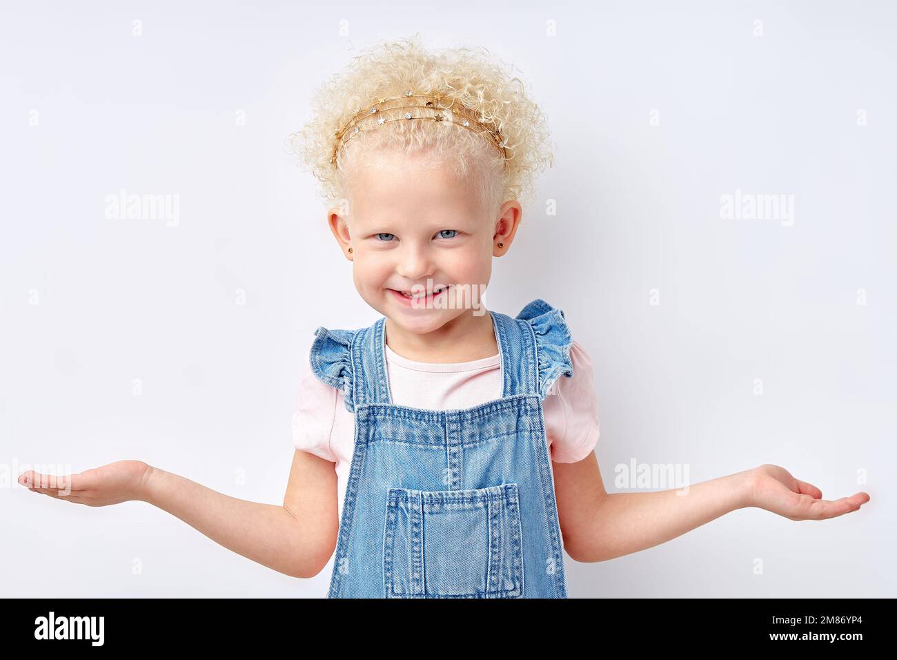 Kleine weiße Blondine verwirrtes Kind nettes Mädchen, 5 Jahre alt, die Hände streut, Geste, Kamera isoliert auf weißem Studiohintergrund, Chil Stockfoto