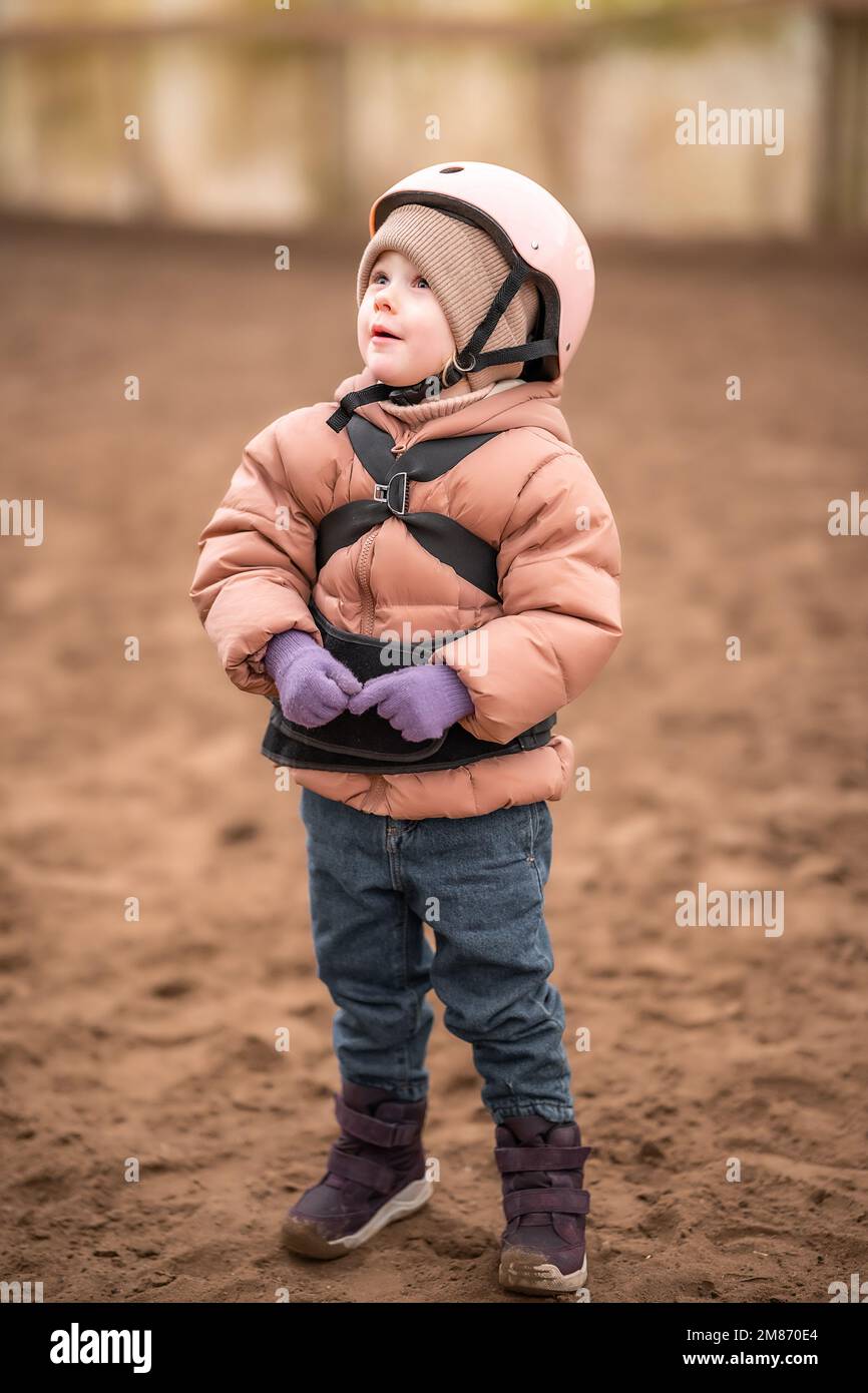 Porträt eines kleinen Mädchens in Schutzjacke und Helm vor dem Reitstunden Stockfoto