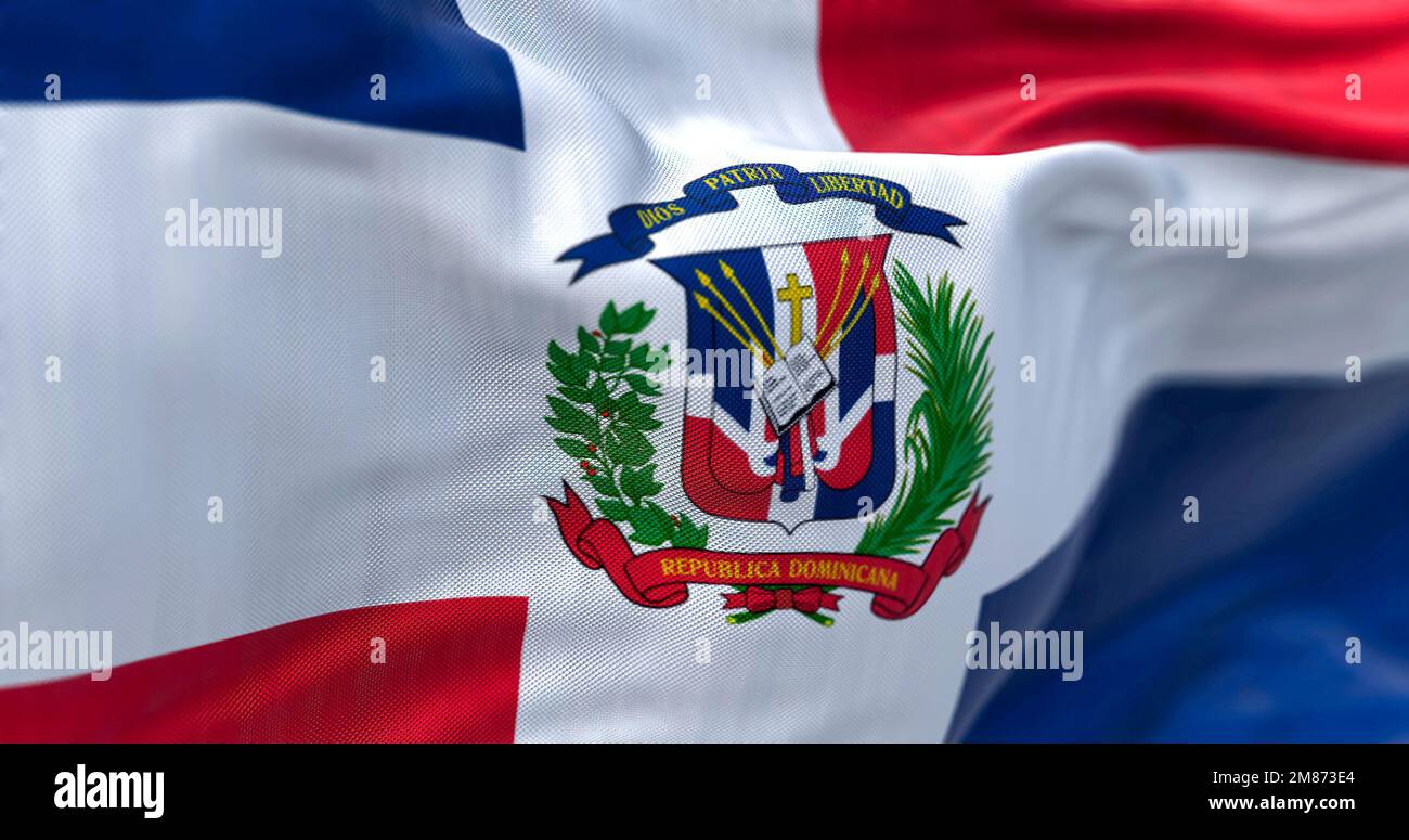 Nahaufnahme der Flagge der Dominikanischen Republik. Rote und blaue Flagge mit weißem Kreuz, Wappen in der Mitte. Geriffelter Stoff. Strukturierter Hintergrund. Selektiv für Stockfoto