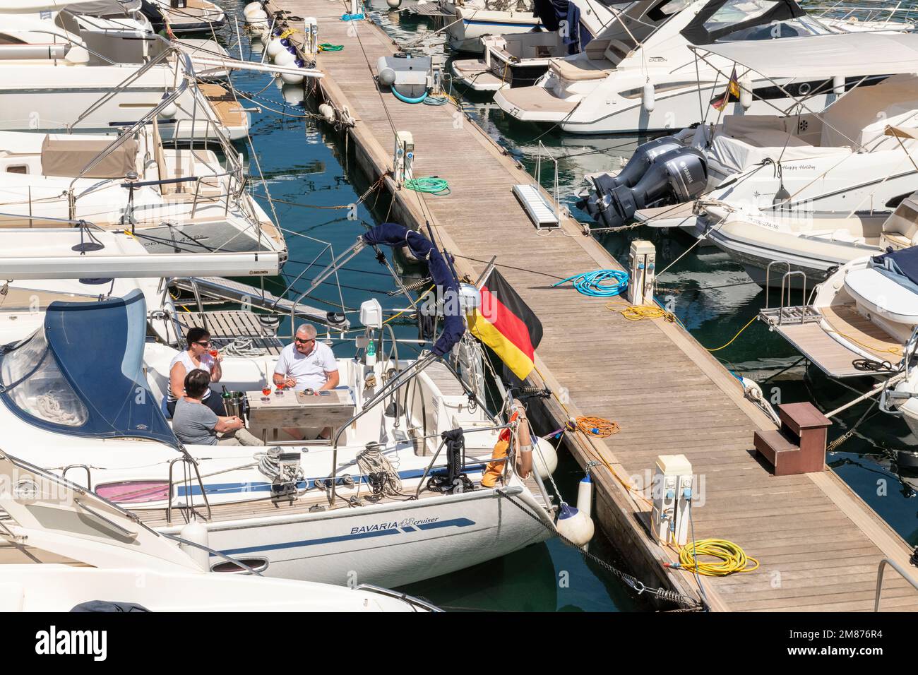 Im Club Nautico von Porto Cristo, Mallorca, genießen drei Freunde den sonnigen Tag auf einem Segelboot. Stockfoto