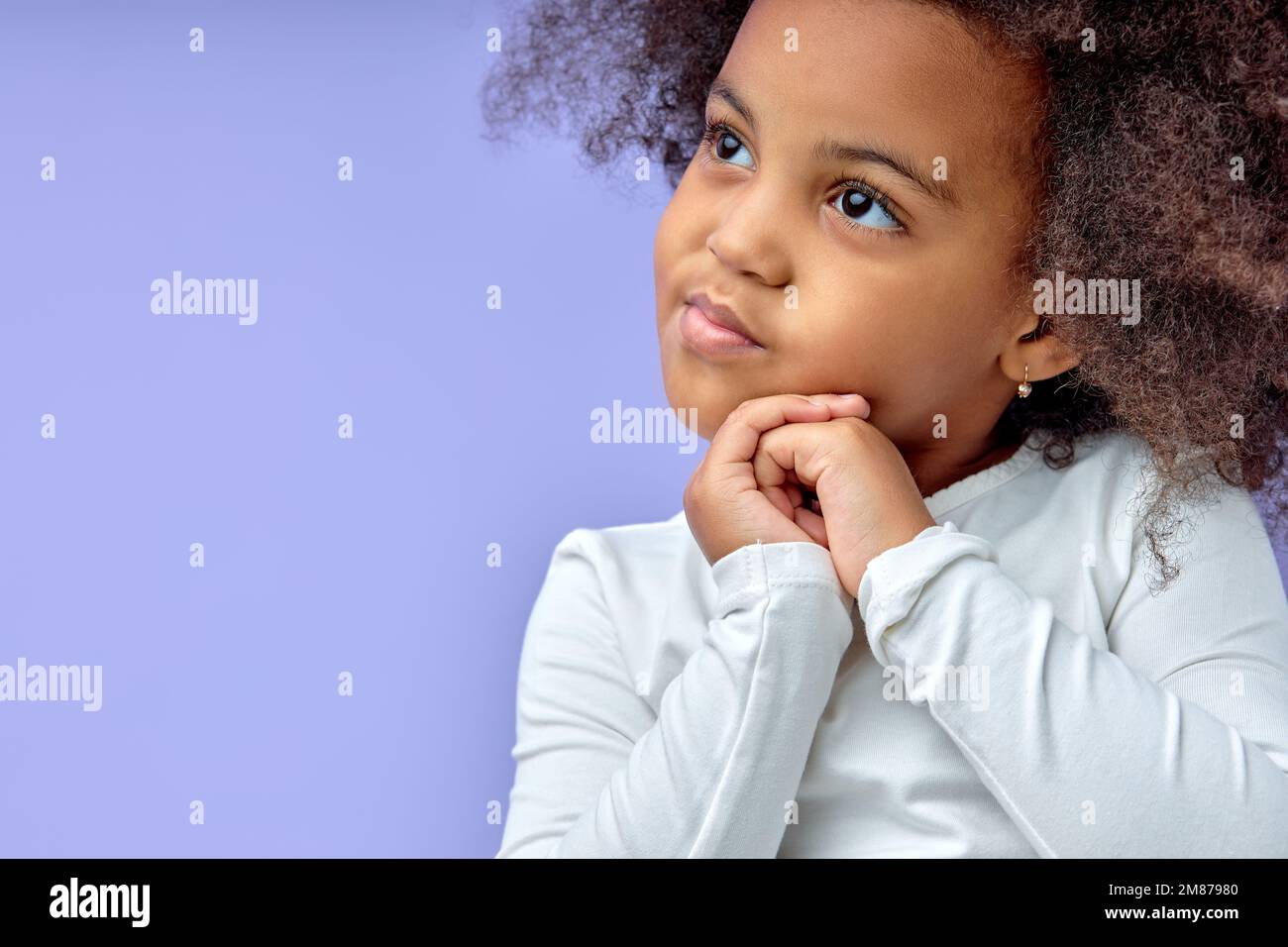 Nachdenkliche kleine schwarze Mädchen sechs Jahre alte Tochter weg auf Kopie Raum denken isoliert auf lila Hintergrund, lustige Kind träumen von etwas Stockfoto
