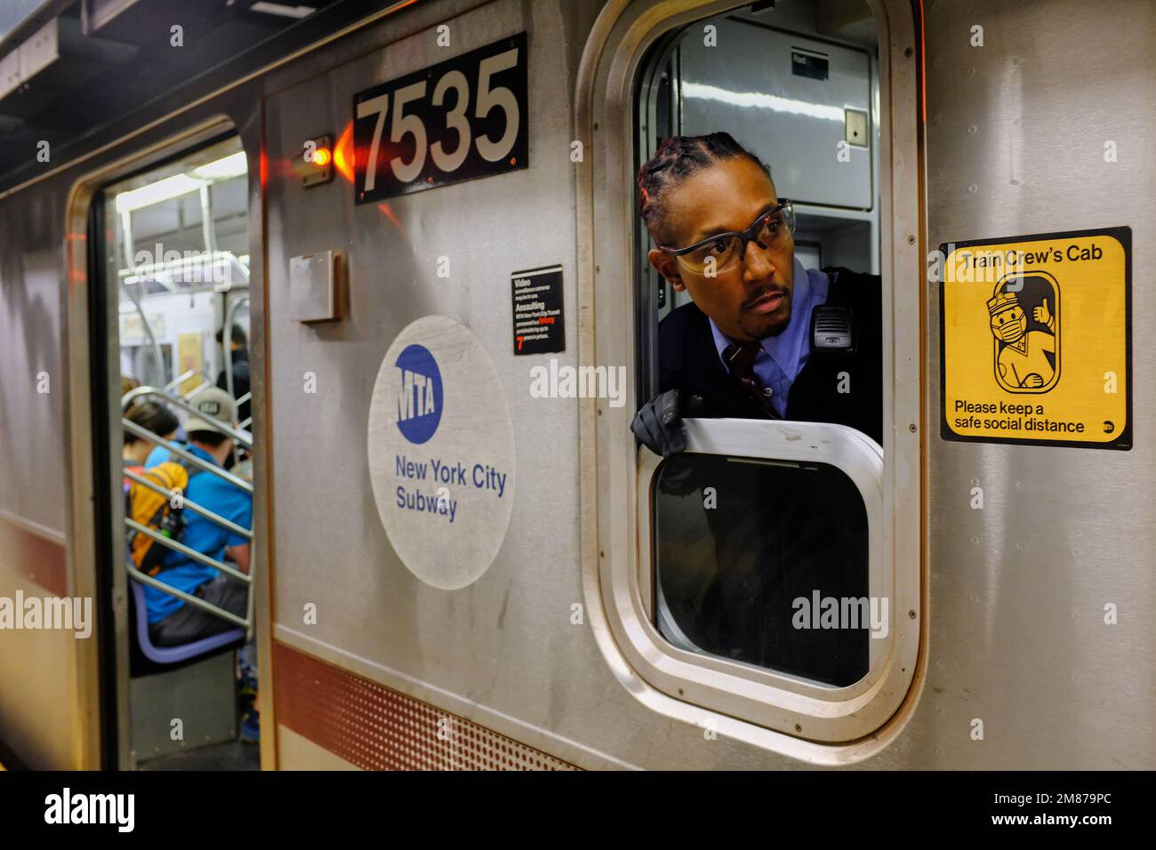 Ein New York City U-Bahn-Schaffner, der aus dem Taxi des Zugpersonals schaut, wenn der U-Bahn-Zug einen Bahnhof erreicht. New York City. New York. New York. USA Stockfoto