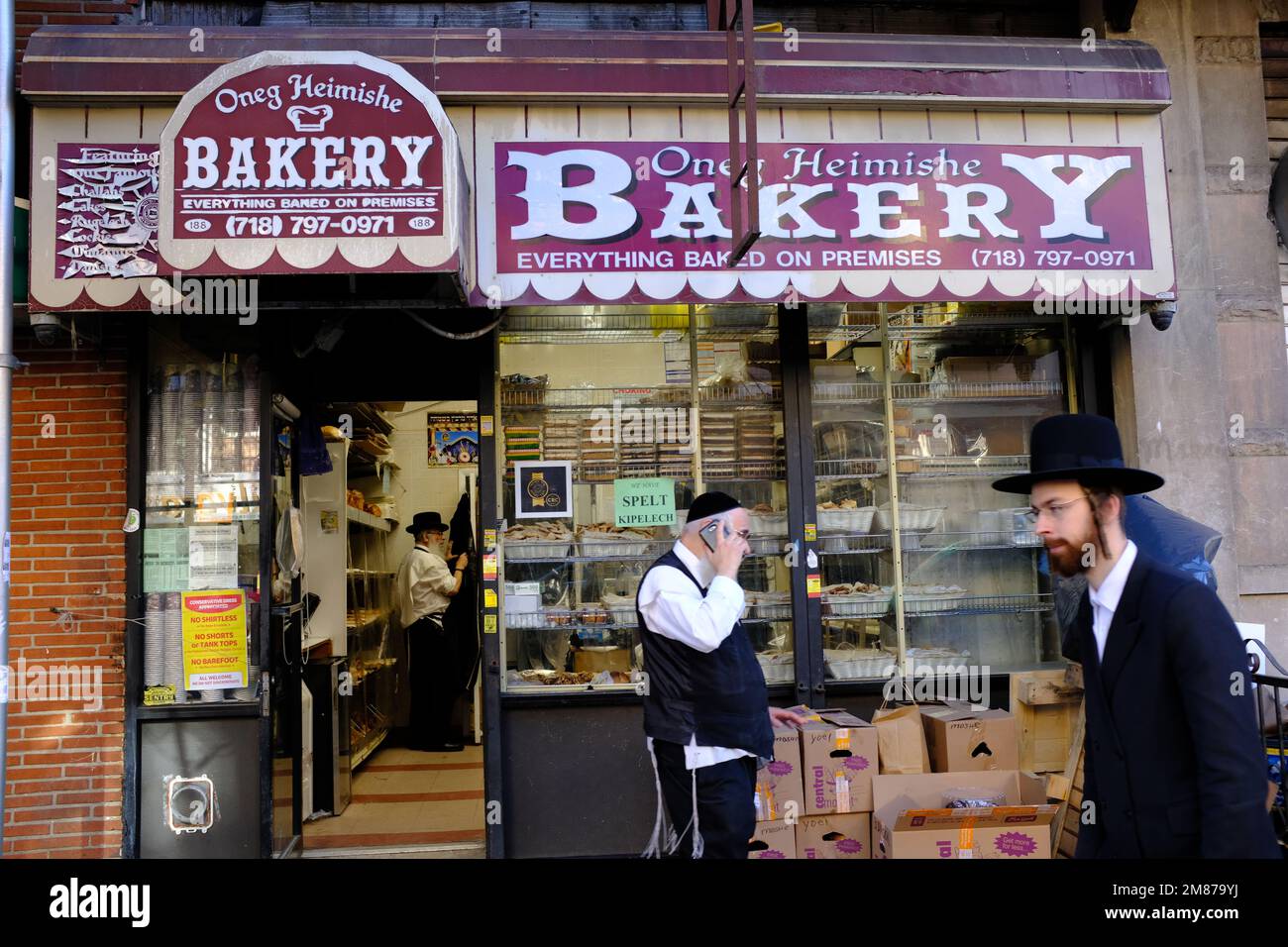 Orthodoxe jüdische Männer gehen vorbei an der Oneg Heimish Bäckerei auf der Lee Avenue.Williamsburg.Brooklyn.New York City.USA Stockfoto