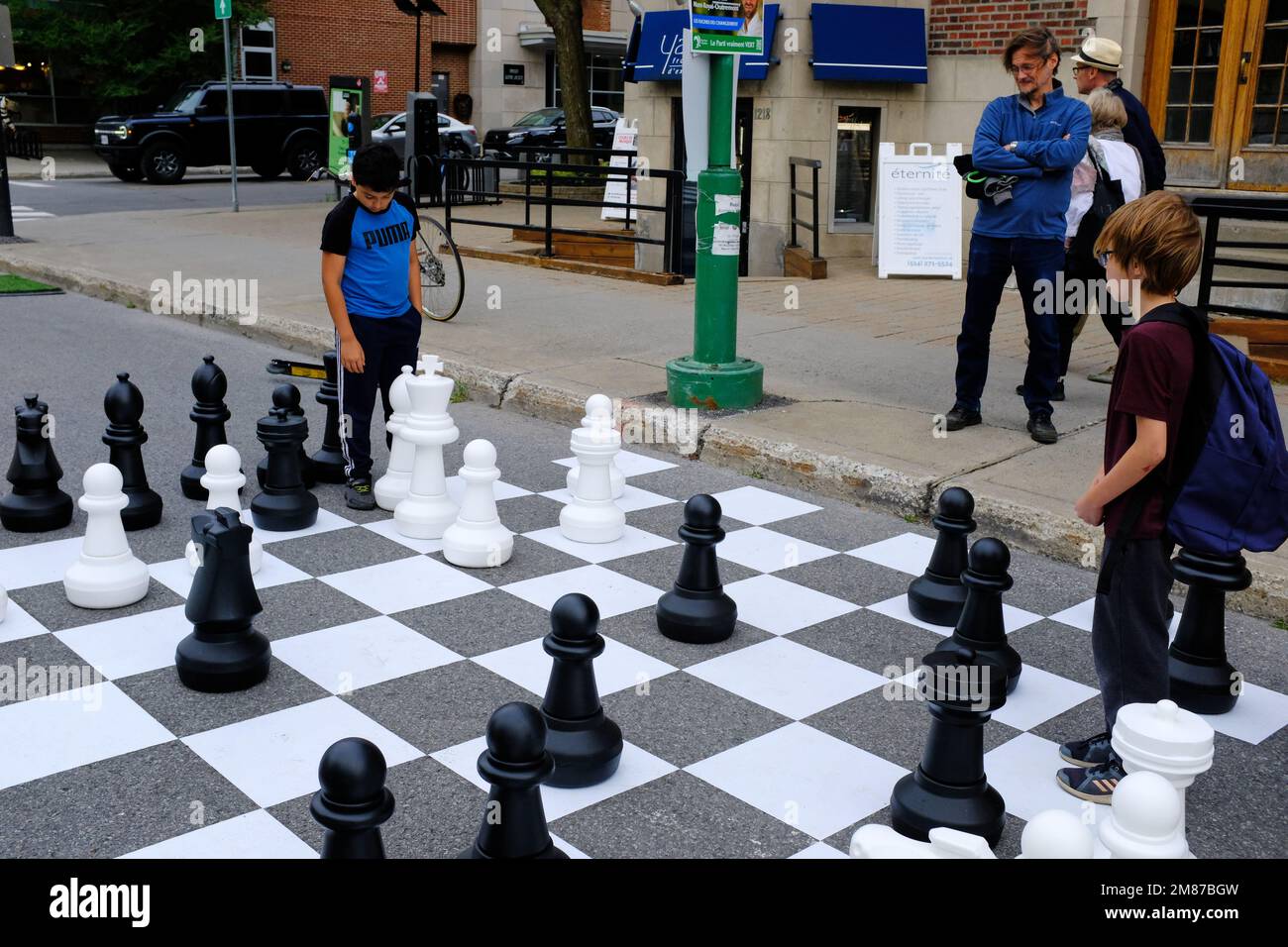 Kinder, die auf der Straße Schach spielen, mit großen Schachfiguren und Schachbrett auf der Straße von Mile enden in Le Plateau Mont Royal.Montreal.Quebec.Canada Stockfoto