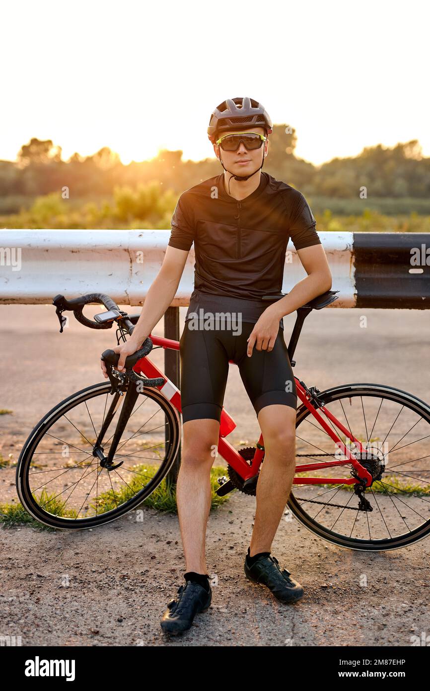 Selbstbewusster Biker, der sich während der Radtour in der Natur ausruht. Ein gutaussehender, weißer Sportler mit Radausrüstung, der draußen trainiert. Reise A Stockfoto