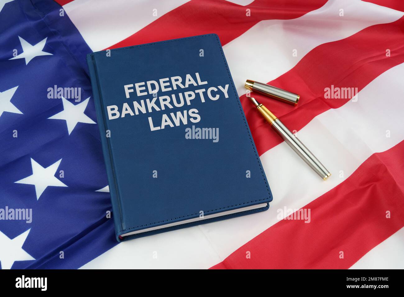 Regelkonzept. Auf der US-Flagge liegen ein Stift und ein Buch mit der Aufschrift "FEDERAL INSOLVENZRECHT" Stockfoto