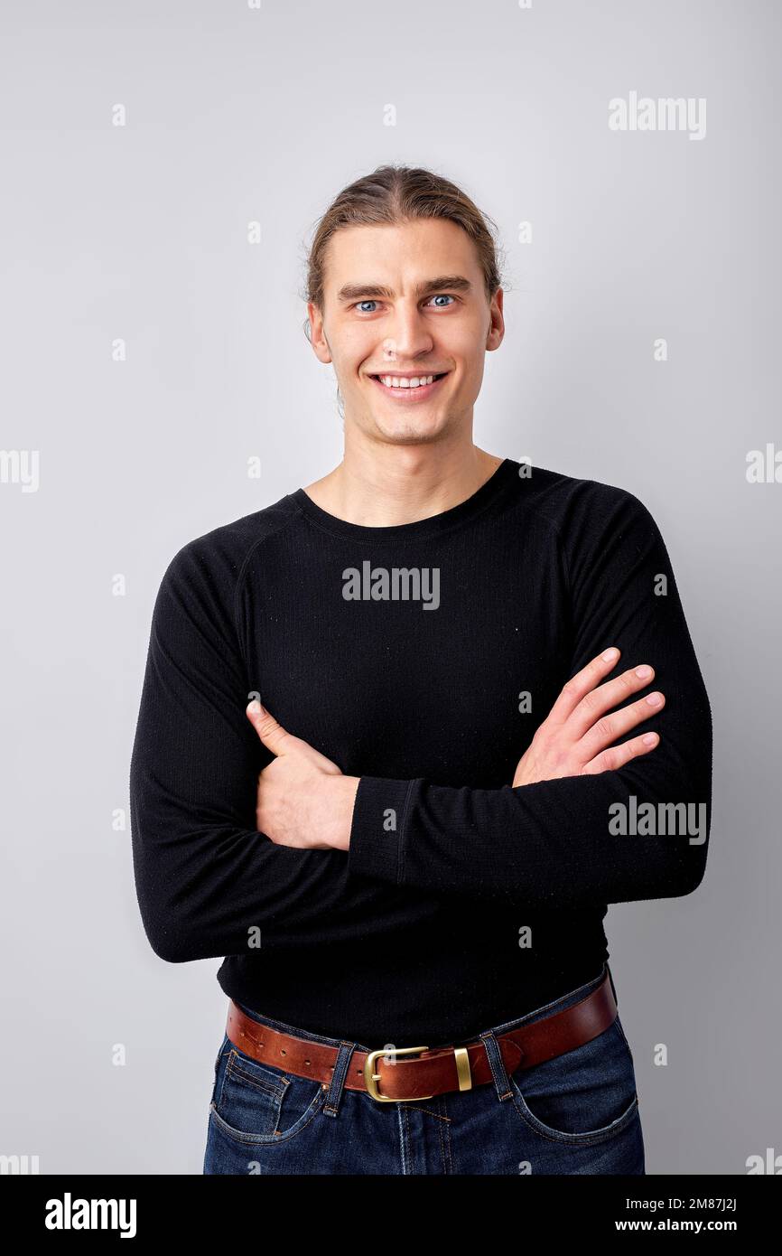 Porträt eines jungen europäischen Mannes in einem lässigen schwarzen Hemd, der vor der Kamera posiert, mit gekreuzten Armen. Hübscher Kerl, der fröhlich und fröhlich aussieht. Isolate Stockfoto