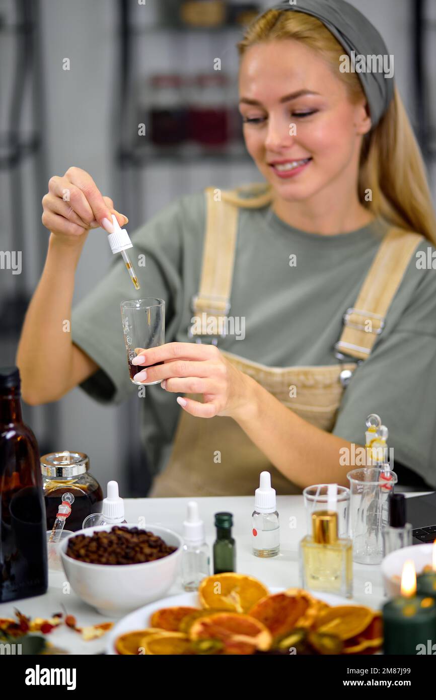 Parfümerie mit Pipettierpipette, um Duft und ätherisches Öl in einer anderen Flasche zu mischen, während der Prozess der Zubereitung des schönen Dufts für die Parfümherstellung durch Stockfoto