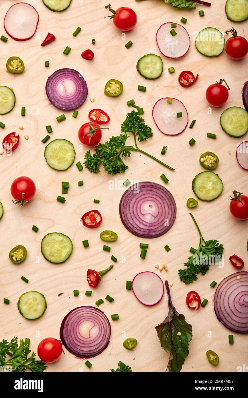 Scheiben von Gurken, Zwiebeln, Grün, Tomatenkirsche beliebte Gewürze Konzept. Draufsicht auf frisches schönes Gemüse auf weichem gelben Hintergrund verstreut, Stockfoto