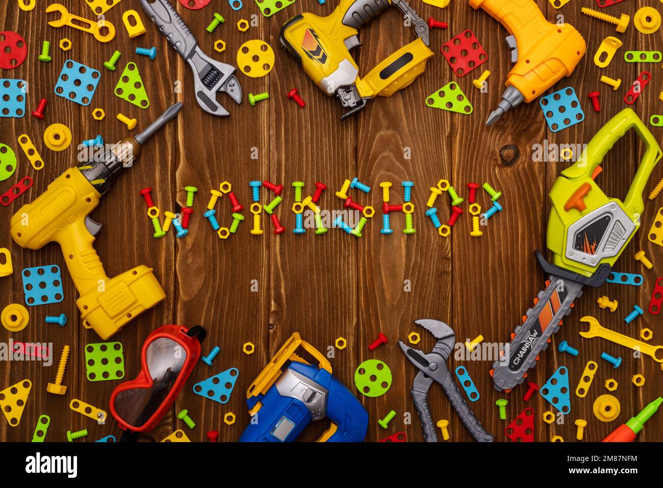 Spielzeugwerkzeuge, Bolzen und Muttern mit TEXTWERKSTATT auf Holzhintergrund Stockfoto