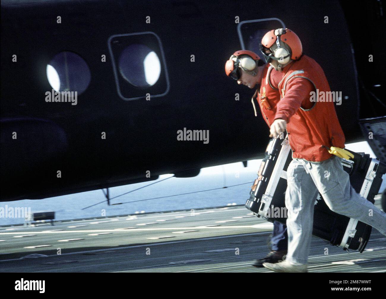 Seemann des Seeschiffs SS PFC. EUGENE A. OBREGON (T-AK-3006), Fracht über das Hubschrauberdeck transportieren, um mit einem Marine-Hubschrauber hochgehoben zu werden. Das Schiff nimmt an der ersten strominternen Entladeübung eines Seeschiffs auf offener See Teil. Ausrüstung und Vorräte werden von der 6. Marine Amphibienbrigade vom Schiff entladen und mit Feuerzeug zur Küste gebracht, als Teil der Übung Solid Shield '87. Betreff Betrieb/Serie: MASSIVER SCHILD '87 Land: Atlantik (AOC) Stockfoto