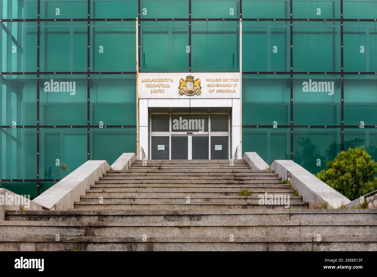 Kutaisi, Georgia, 06.06.21. Eingang zum Haus der Regierung von Georgien in Kutaisi, ein modernes, verlassenes Gebäude aus grünem Glas. Stockfoto