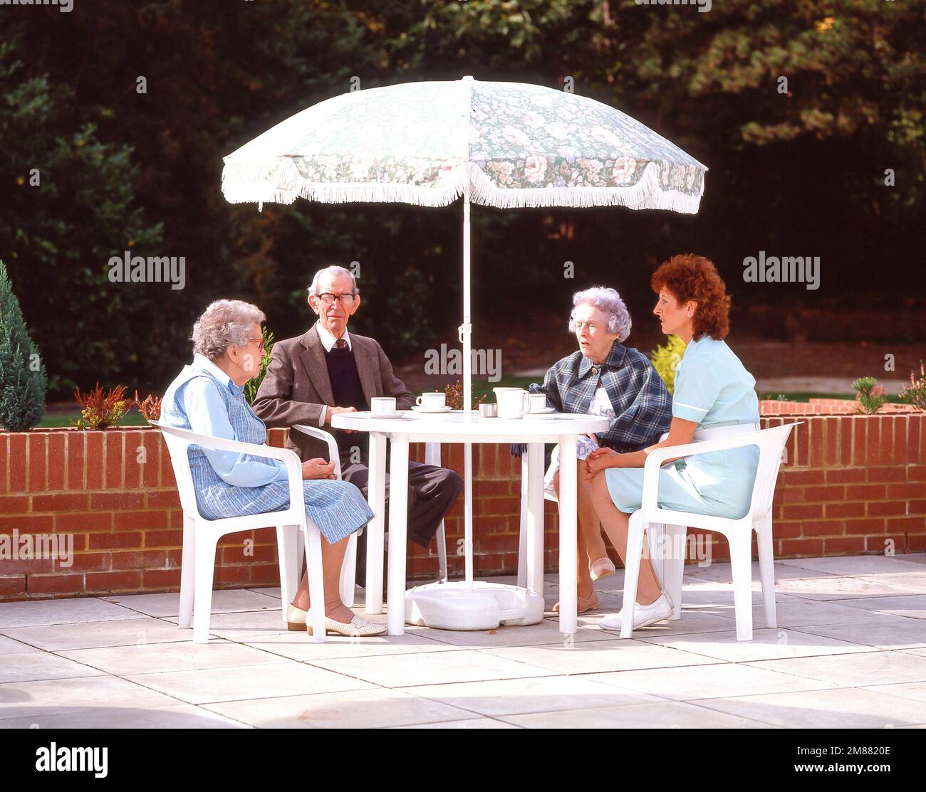 Einwohner, die Tee im Terrassengarten des Pflegeheims, Surrey, England, Vereinigtes Königreich, trinken Stockfoto