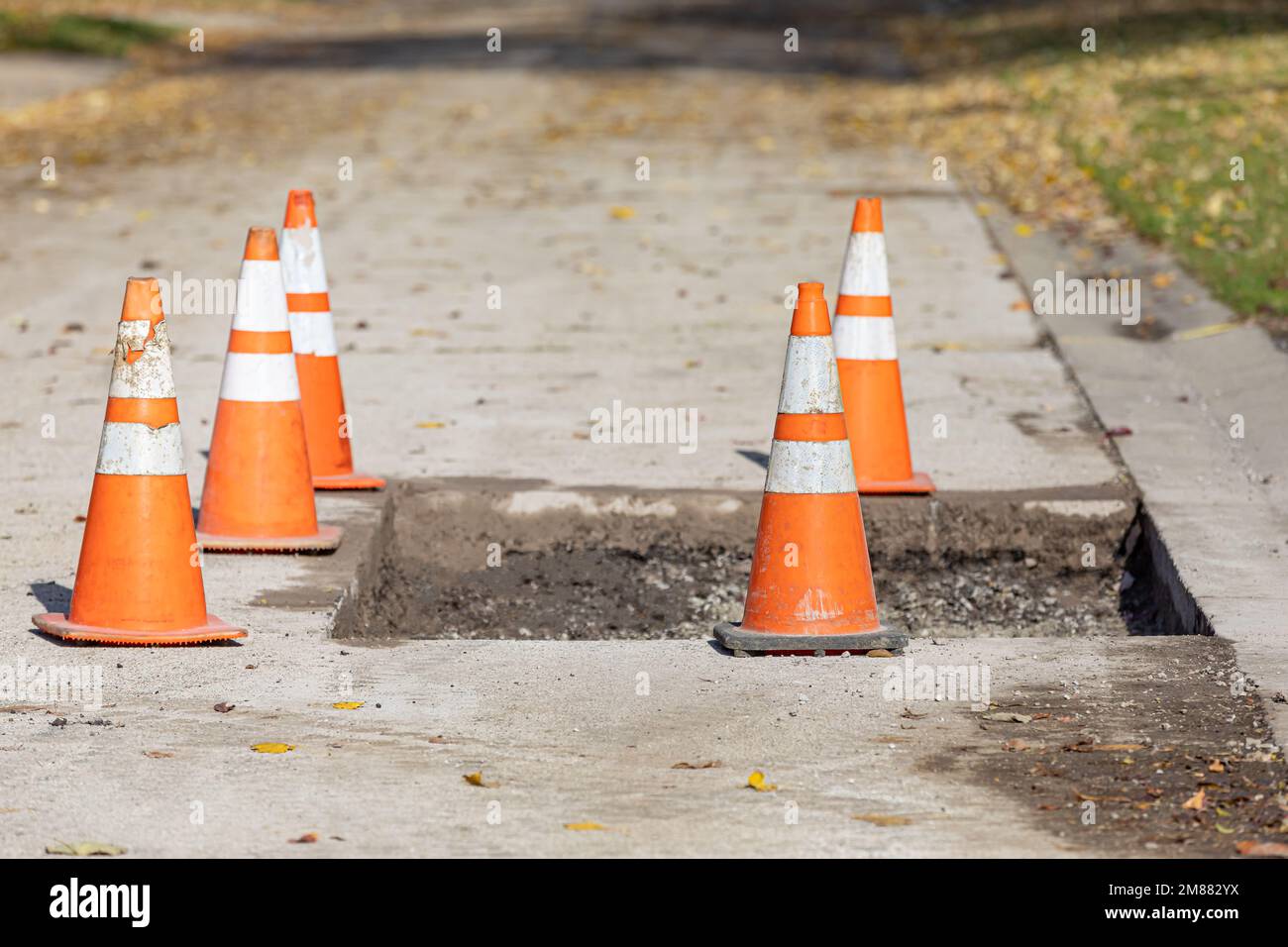 Straßenreparatur in der Stadt mit orangefarbenen Verkehrskegeln. Konzept für Straßenbau, Instandhaltung und Infrastrukturfinanzierung. Stockfoto