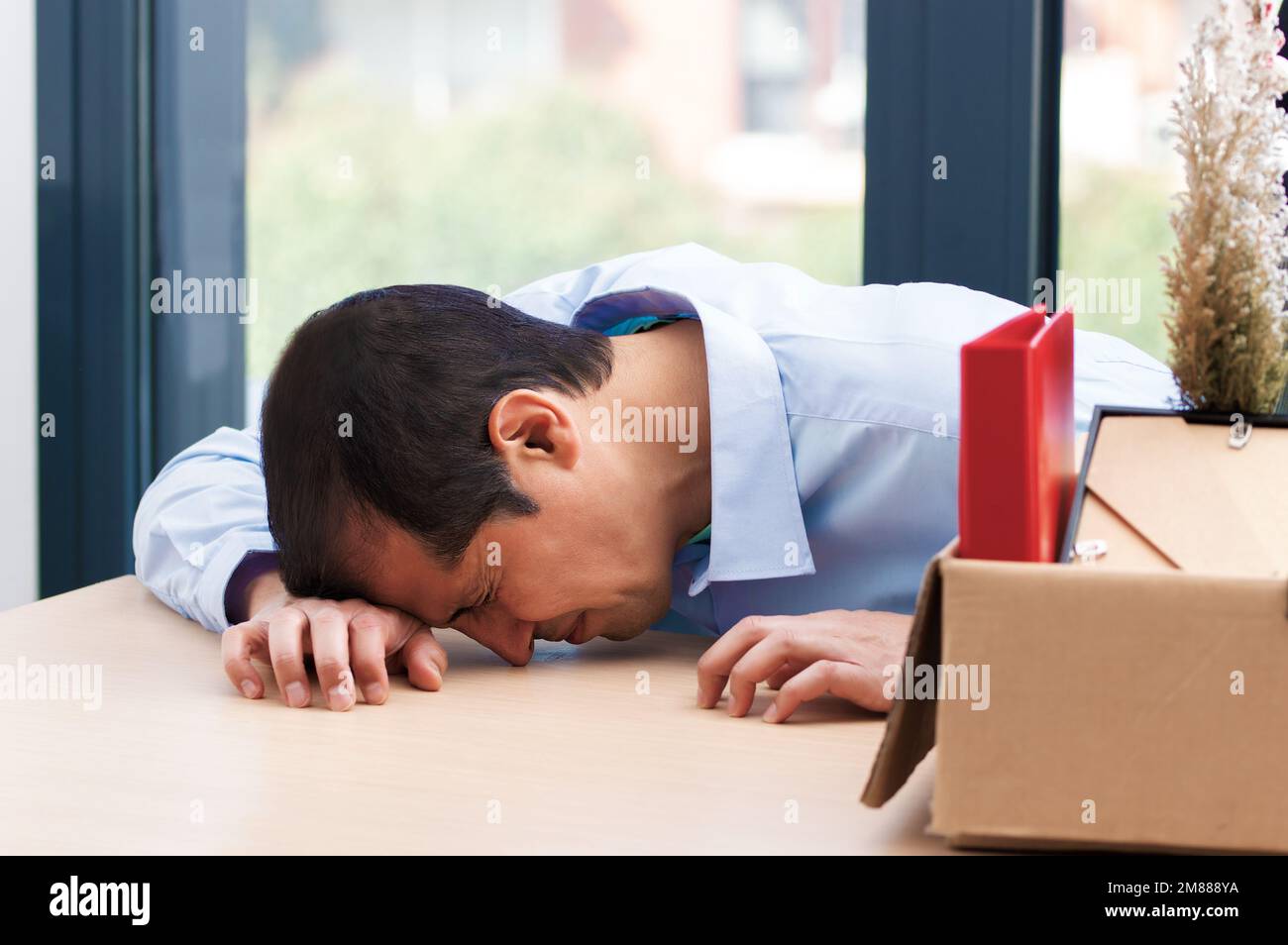 Ein trauriger gefeuerter Manager, der weint und ihre Sachen auf eine Kiste im Büro packt Stockfoto