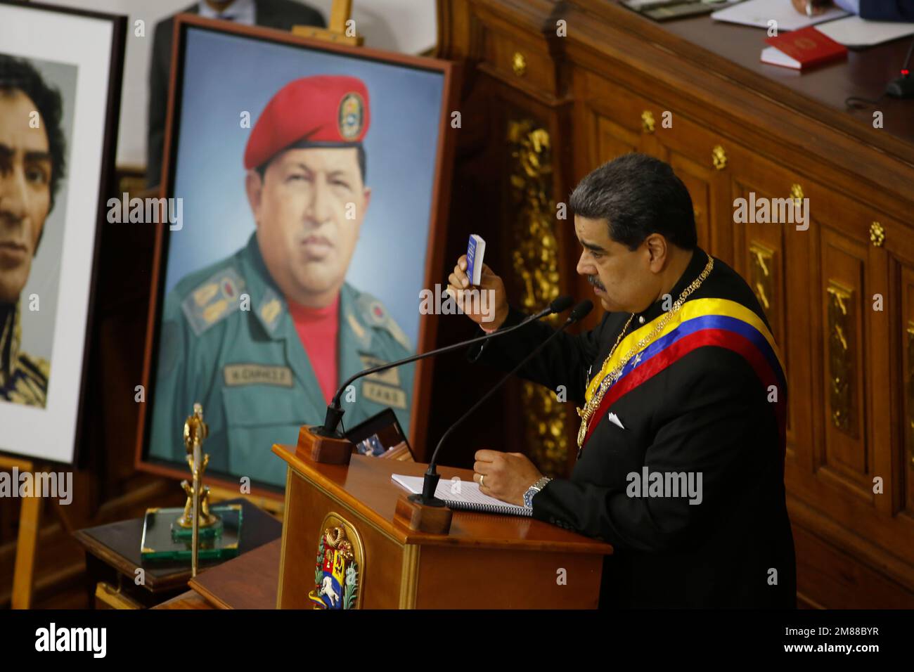 Caracas, Venezuela. 12. Januar 2023. Nicolas Maduro, Präsident von Venezuela, hält die jährliche Rede vor der Nation neben einem Porträt von Hugo Chavez und zeigt eine Miniausgabe der Verfassung im Palacio Federal Legislativo. Kredit: Pedro Rances Mattey/dpa/Alamy Live News Stockfoto