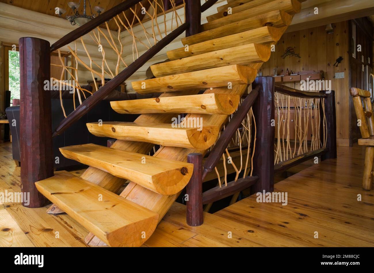Treppen aus weißem Kiefernholz mit Zedernholzgeländern, die zum oberen Stockwerk in einem Blockhaus im skandinavischen Stil führen. Stockfoto