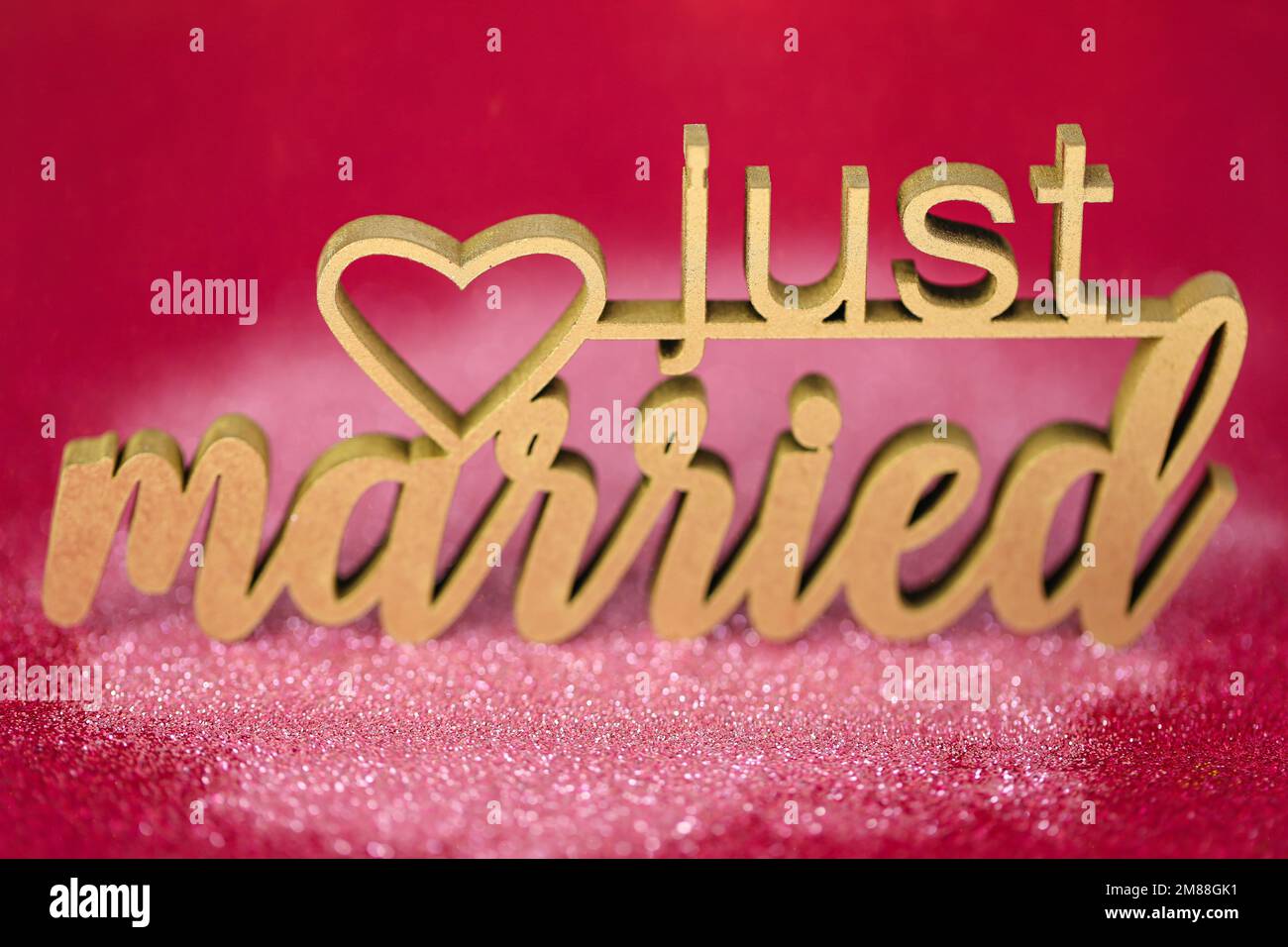 Gerade verheiratete Inschrift auf pinkfarbenem Hintergrund. Hochzeitssymbol. Stockfoto