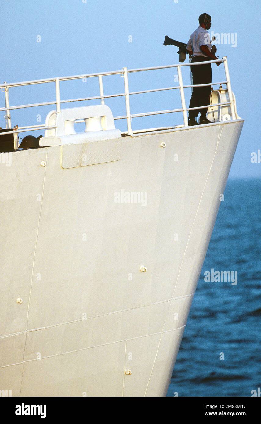 Ein Seemann steht neben einem M60-mm-Mehrzweck-Maschinengewehr auf dem Bug des verschiedenen Flagschiffs USS LASALLE (AGF 3) Wache. Land: Unbekannt Stockfoto