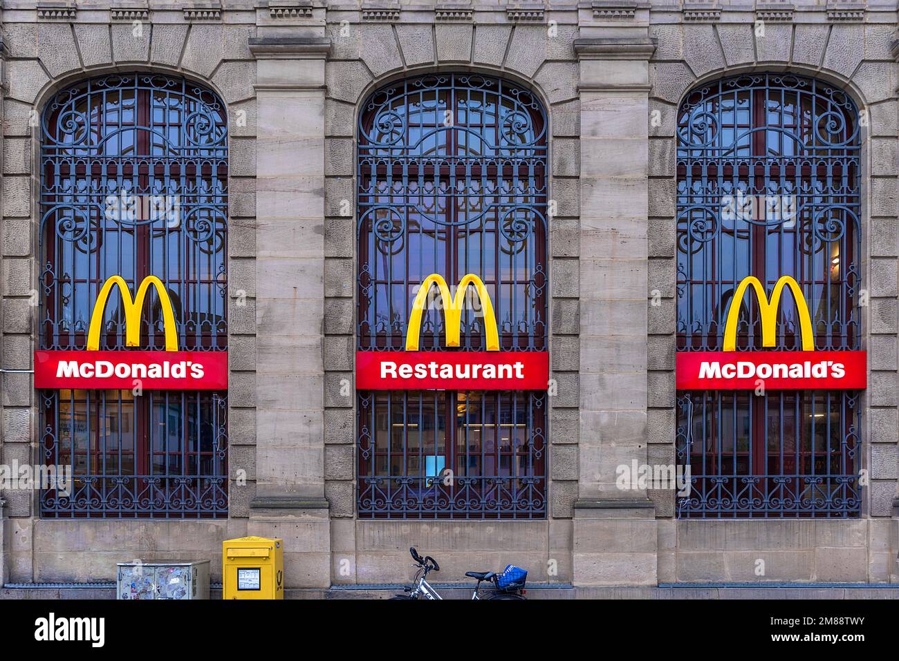MC-Donald-Logos auf einer denkmalgeschützten Fassade des ehemaligen Hauptpostamts Erlangen, Mittelfrankreich, Bayern Stockfoto