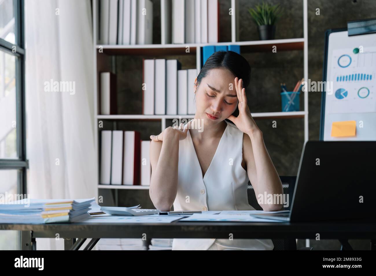 Geschäftsfrau überlastet mit Laptop Computer und Nackenschmerzen bei der Arbeit im Büro, Mädchen Stress und Krankheit chronisch mit Büro Syndrom, Gesundheit und Stockfoto