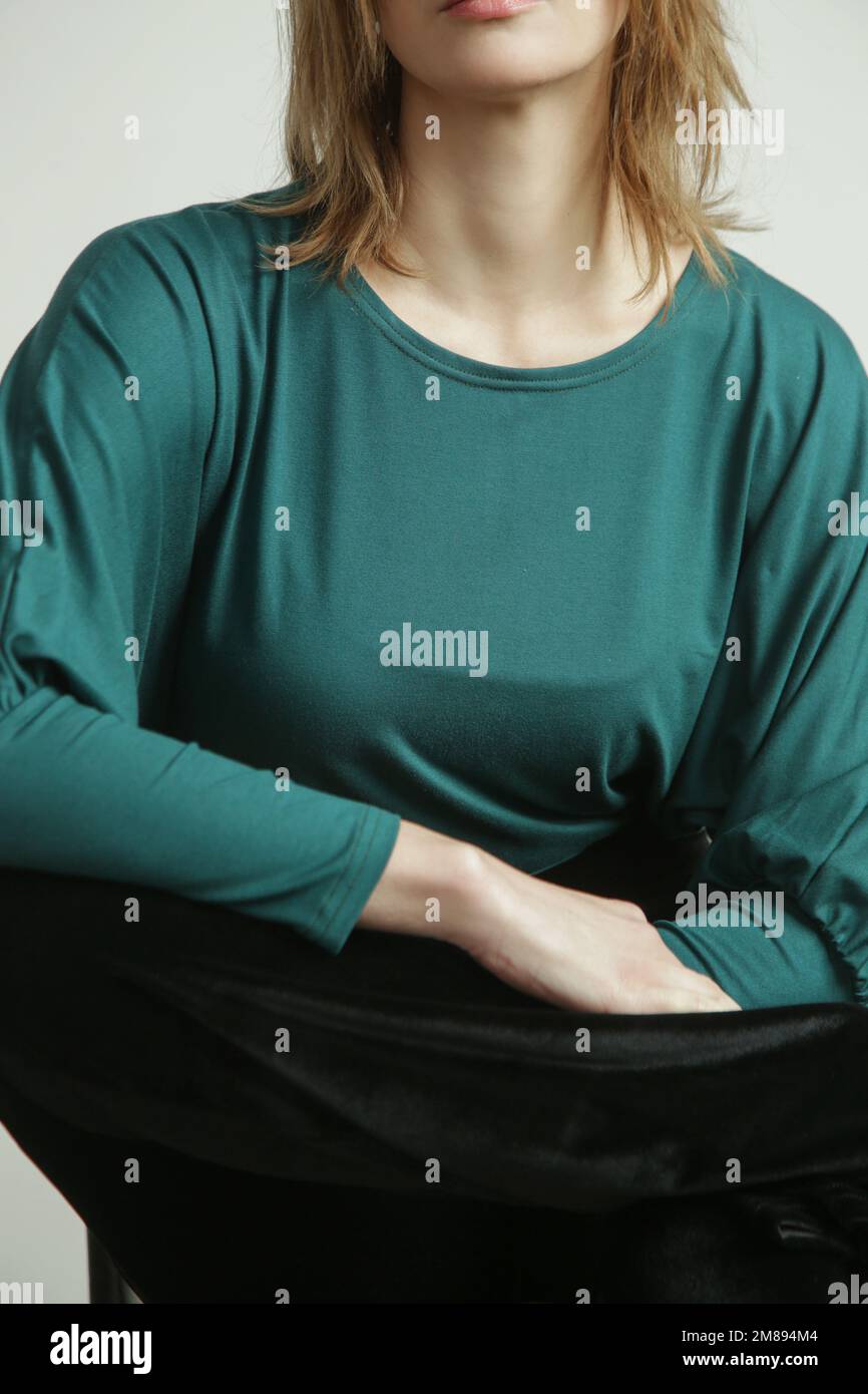 Studiofoto eines jungen weiblichen Models, das ein grünes langärmeliges Hemd aus biologischer Baumwolle trägt. Bequeme, nachhaltige Mode. Stockfoto