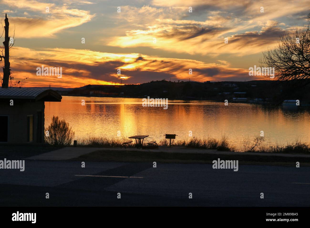 Wunderschöner Sonnenuntergang am Himmel im Inks Lake State Park Burnet Texas USA. Die Hütte und der Picknicktisch am Ufer sind bereit für eine Familie, um den Urlaub zu genießen. Stockfoto