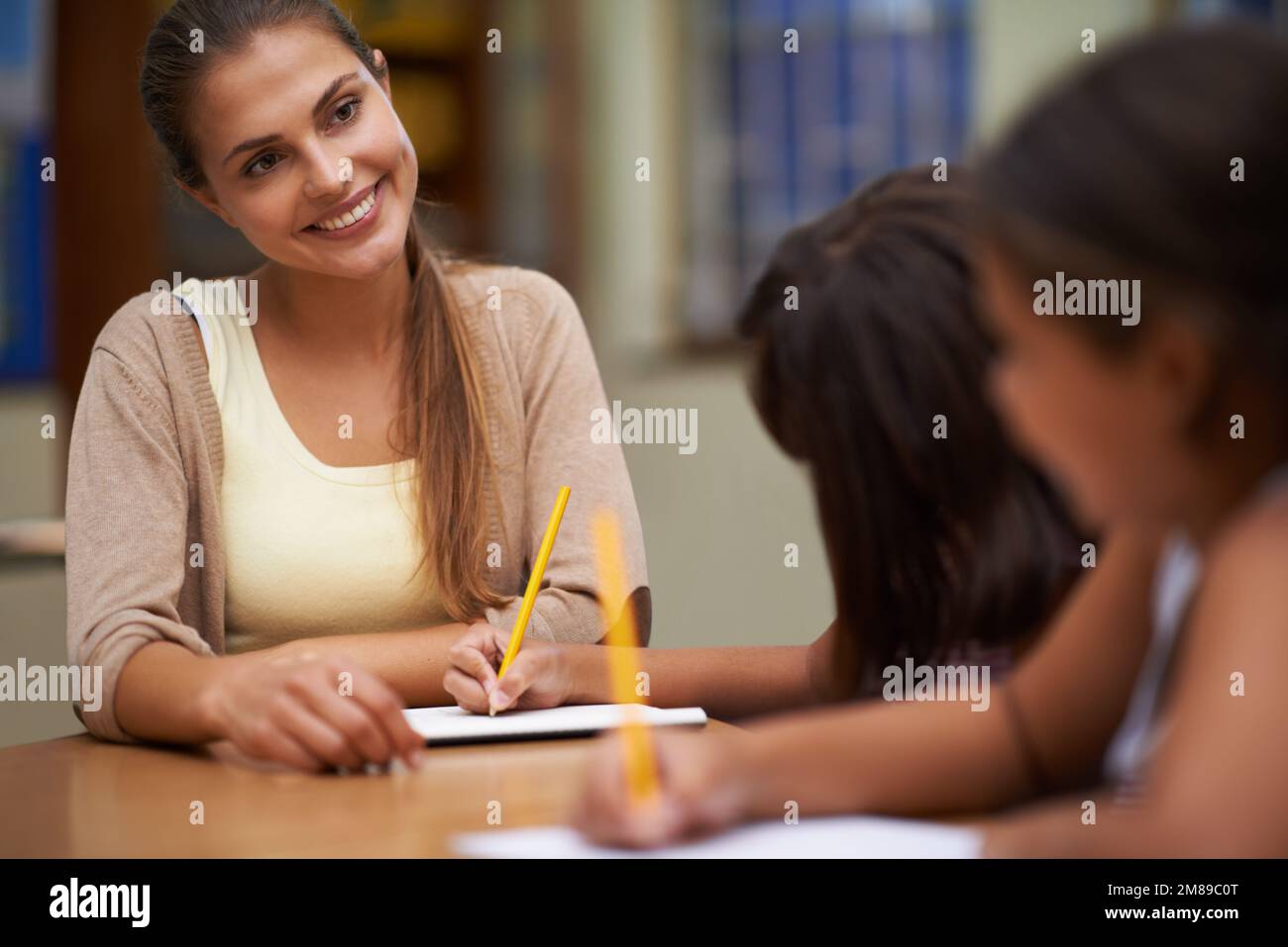 Sie investierte in ihre Zukunft. Eine Lehrerin, die ihren Schülern bei der Arbeit im Klassenzimmer hilft. Stockfoto