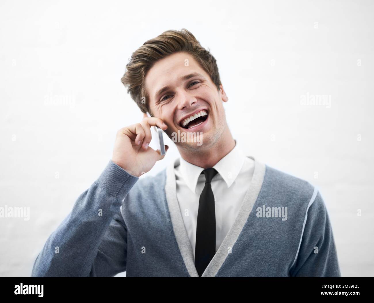 Schön, von Ihnen zu hören. Ein junger Mann, der lacht und mit seinem Handy spricht. Stockfoto
