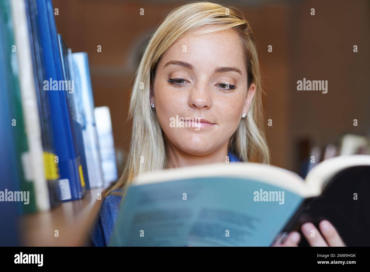 Unsere Universität hat die beste Bibliothek. Ein attraktiver junger Student, der ein Buch lese. Stockfoto