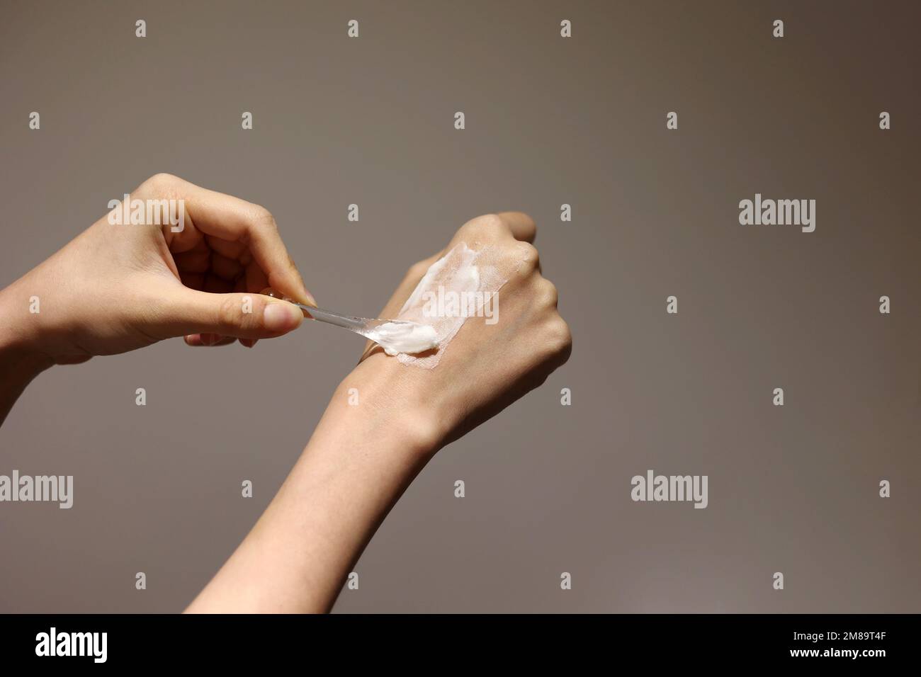 Kosmetische Creme mit Spatel auf die Hände auftragen Stockfoto