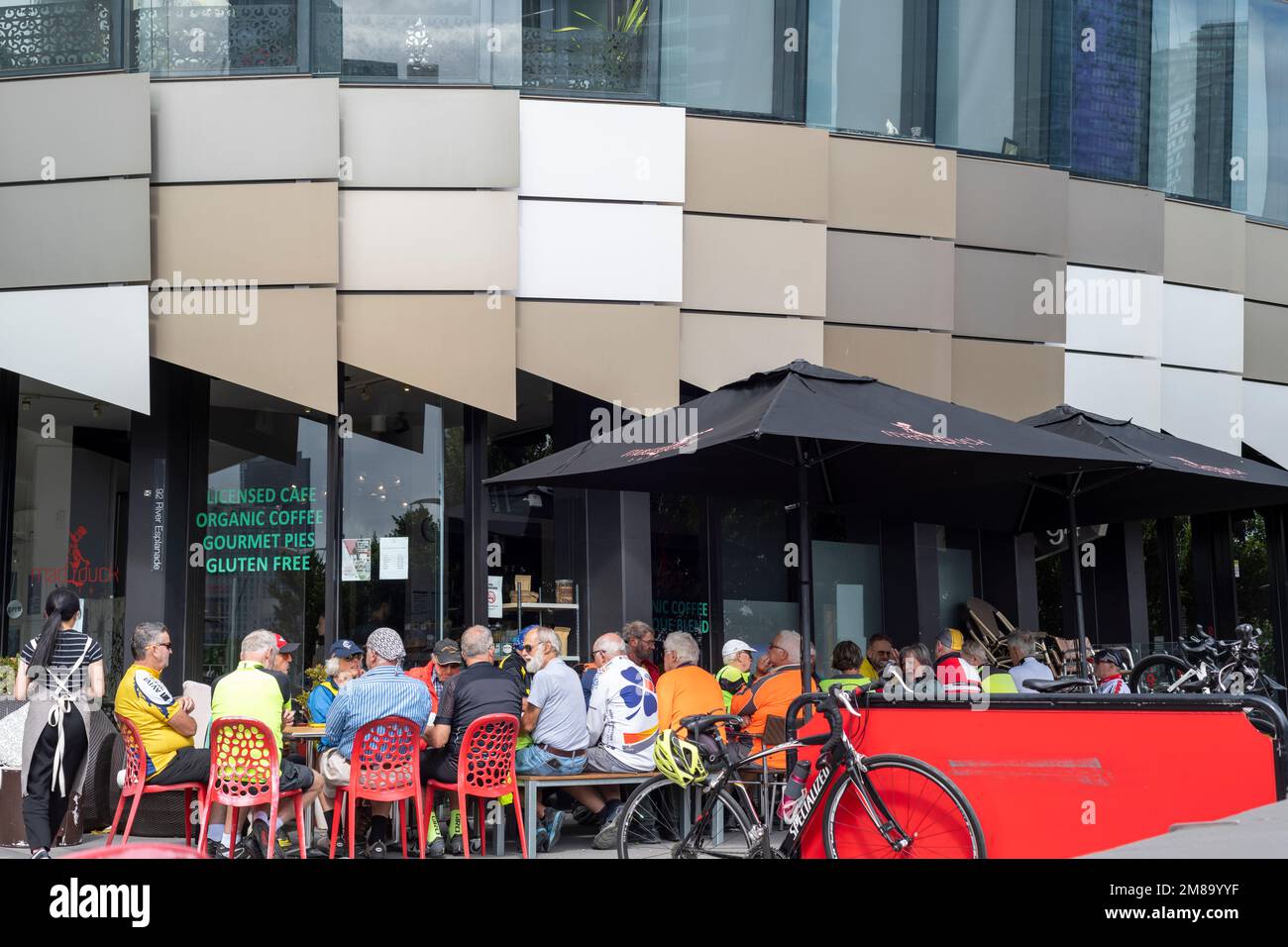 Viele reife Radfahrer treffen sich nach einer Fahrt im Geschäftsviertel von Melbourne auf einen Kaffee. Stockfoto